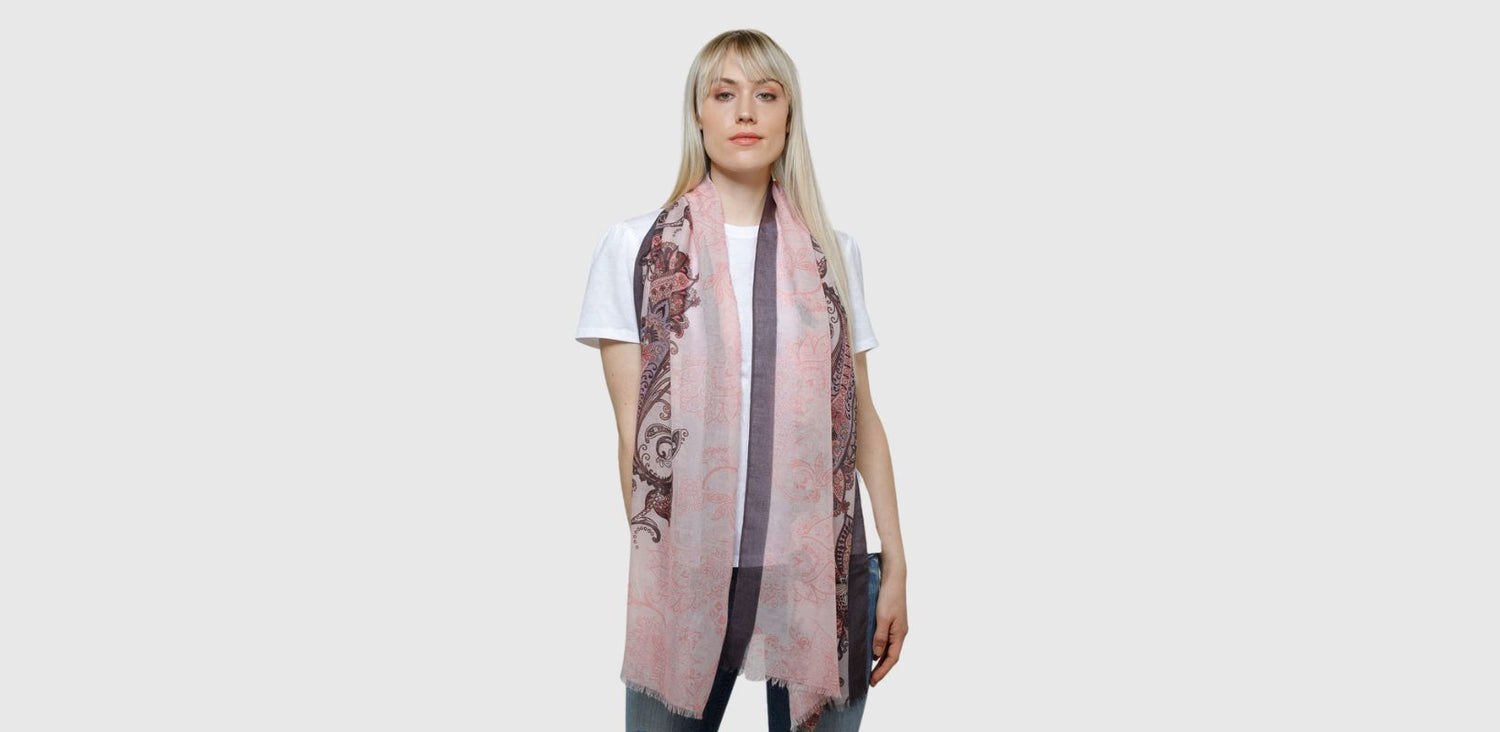 A woman wears a sheer patterned scarf around her neck. It's yellow, rust and a hint of green shows on one side.