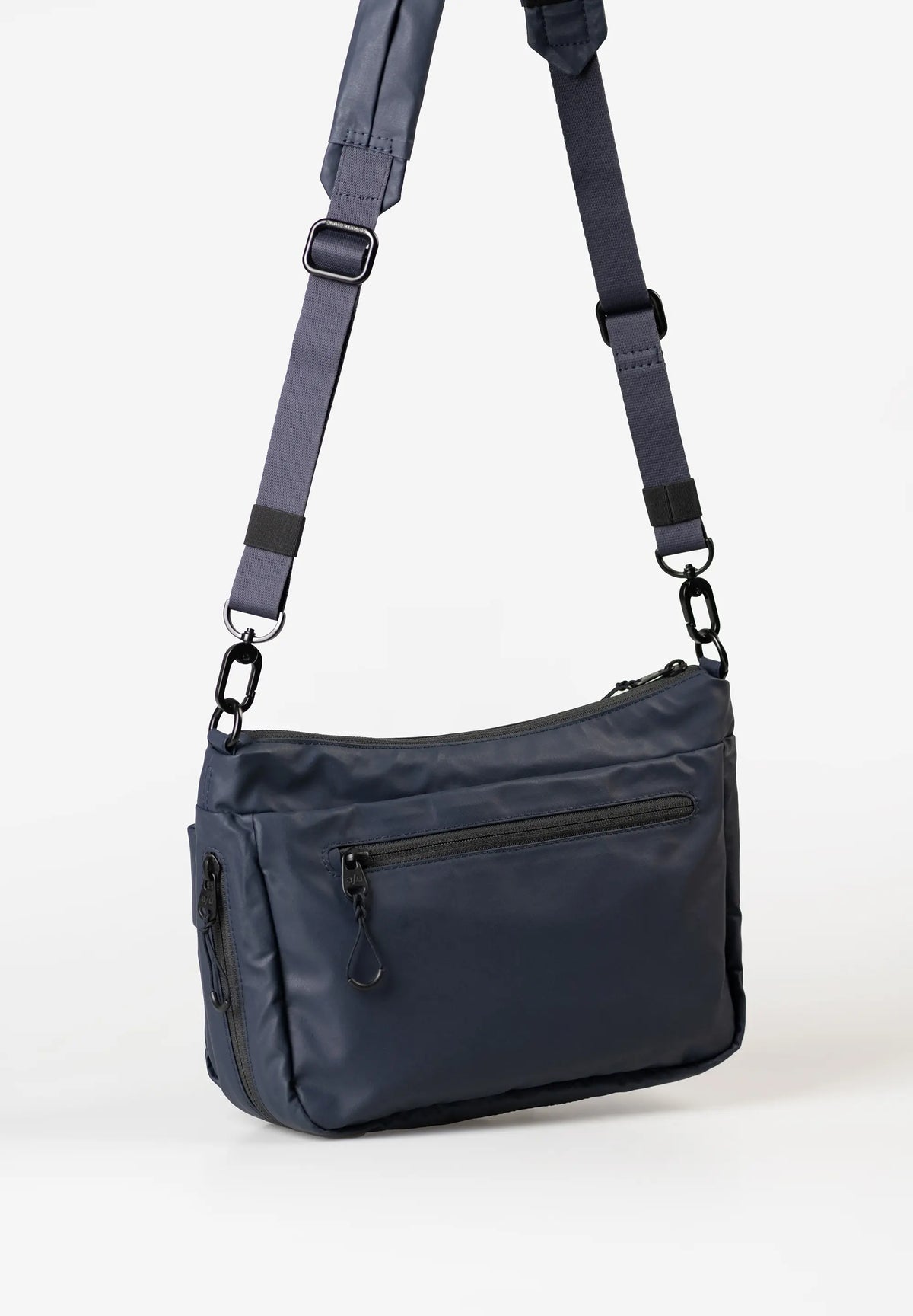 Aunts & Uncles Mogami RE Lite Crossbody Bag. A navy blue nylon crossbody bag with a matching adjustable shoulder strap, black hardware, and a zippered front pocket, shown on a clean white background.