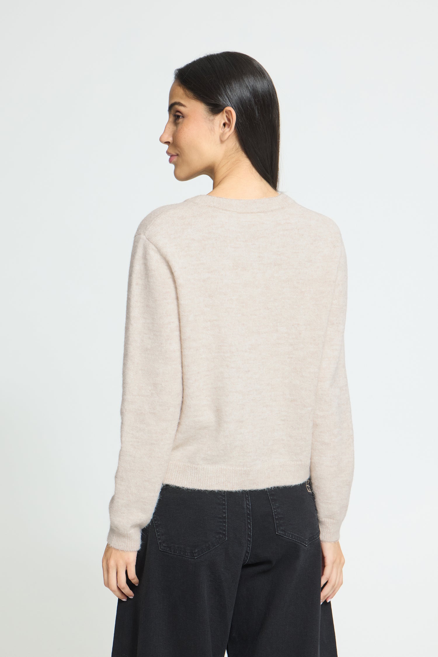 Ichi Fanita Cardigan. A woman shown from the back wearing a light beige knit sweater and dark wide-leg pants against a plain light gray studio background.