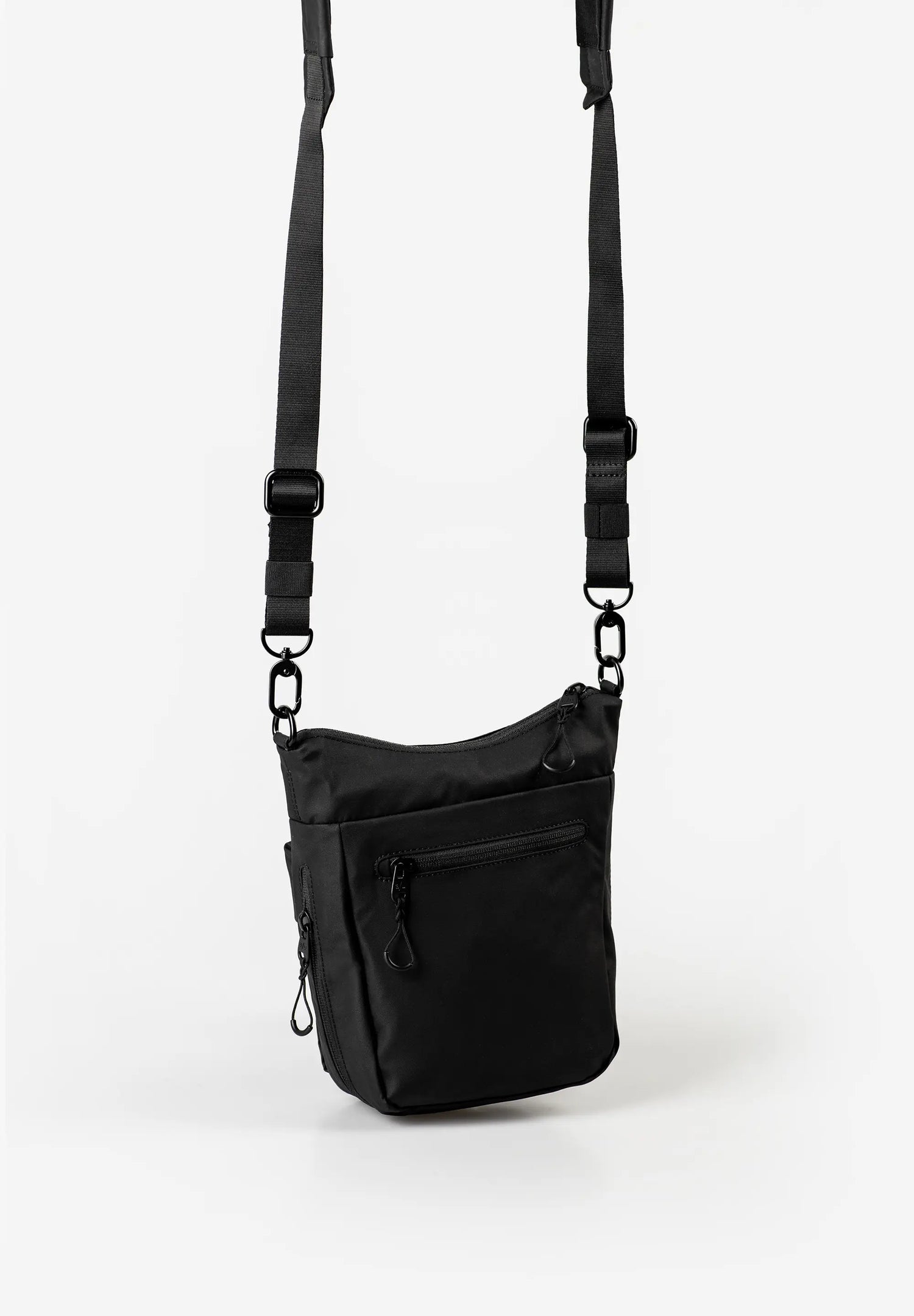 Aunts & Uncles Yura RE Lite Crossbody Bag.A black nylon crossbody bag with an adjustable shoulder strap and a front zippered pocket, shown against a plain white background.