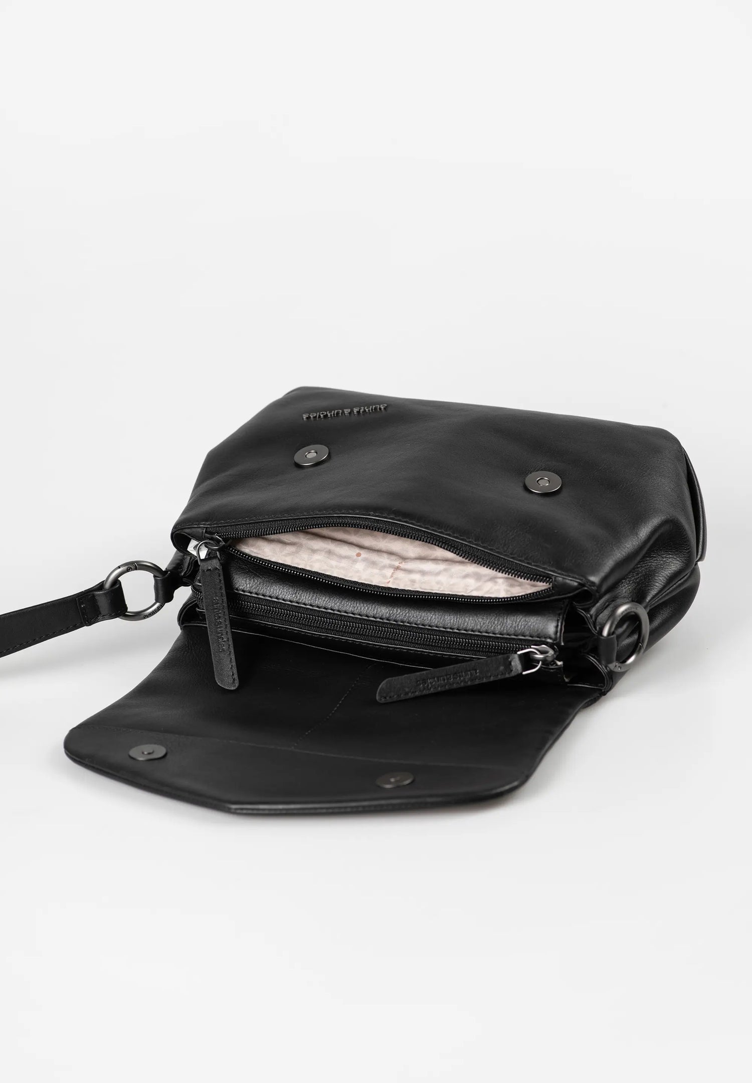 Aunts & Uncles Fern Leather Crossbody Purse. A black leather crossbody bag shown open, displaying its interior lining and zippered compartments, set against a plain light gray background.