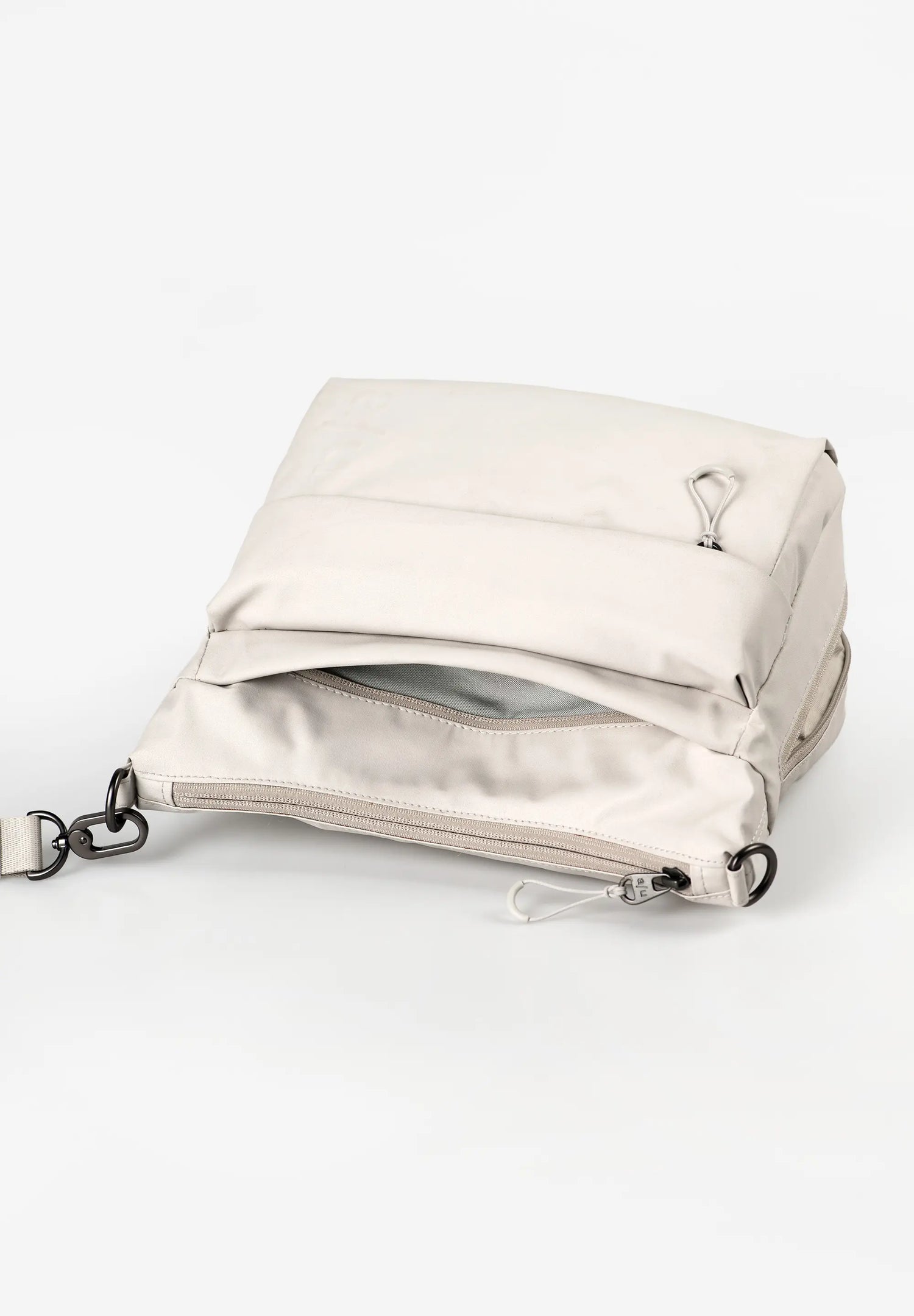 Aunts & Uncles Nanuki RE Lite Crossbody Bag. A light beige nylon crossbody bag with a zippered pocket and silver hardware, shown on a clean white background.
