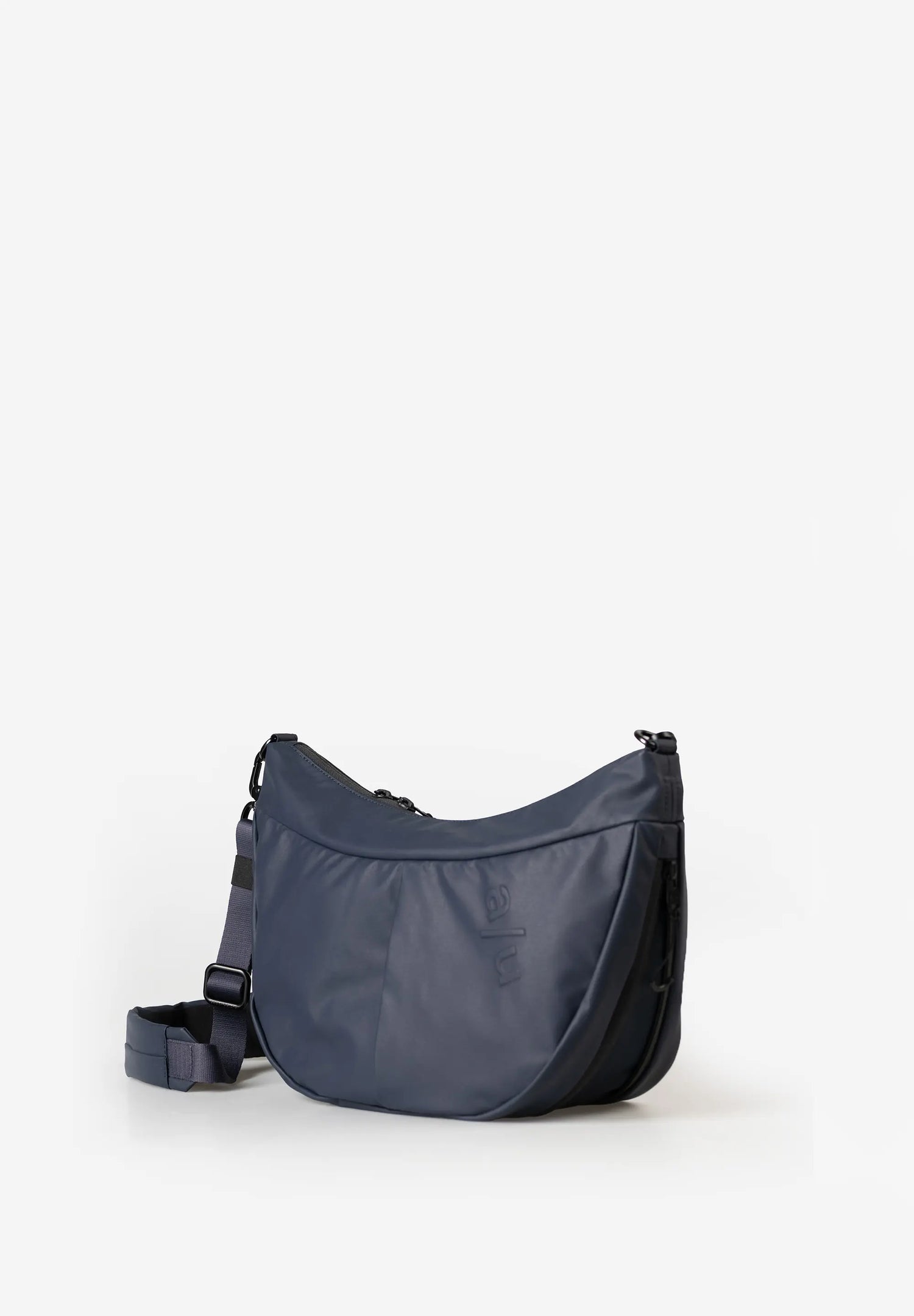 Aunts & Uncles Toyo RE Lite Halfmoon Bag. A navy blue crescent-shaped shoulder bag with a matching adjustable strap, displayed on a clean white background.