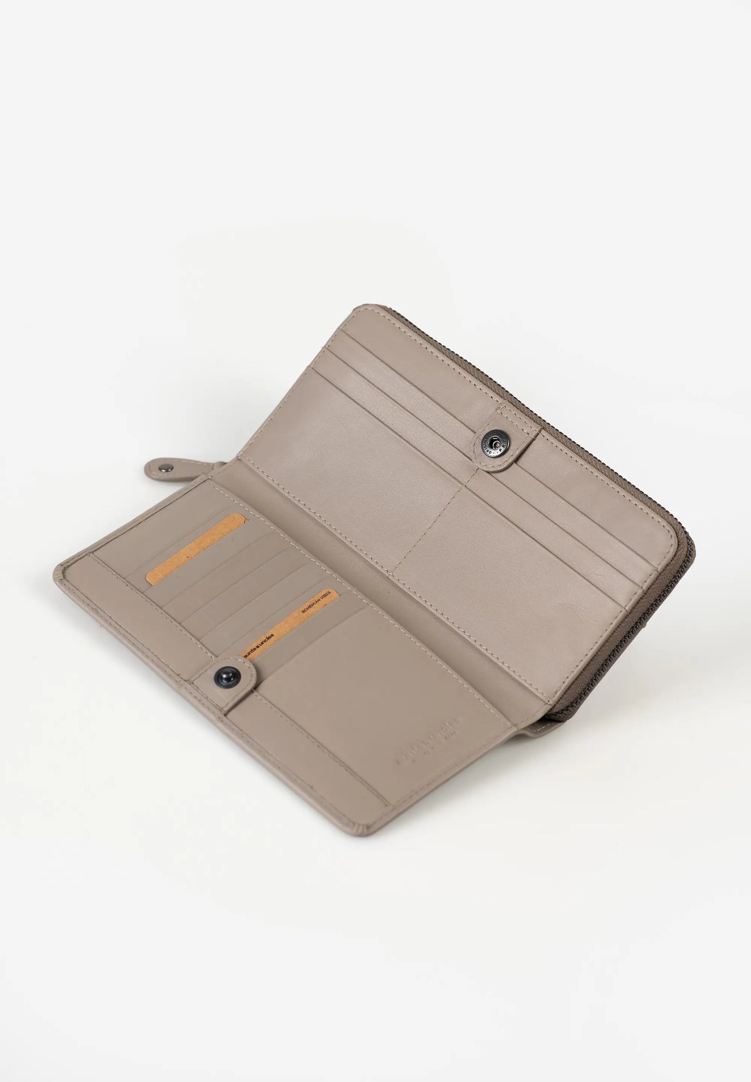 Aunts & Uncles Maple Leather Wallet. A taupe leather wallet shown open, displaying its interior card slots, snap-button closures, and a small orange accent card, set against a plain white background.