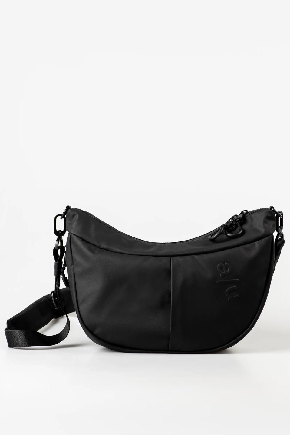 Aunts & Uncles Toyo RE Lite Halfmoon Bag. A black crescent-shaped nylon shoulder bag with a subtle embossed logo on the front, displayed on a clean white studio background.