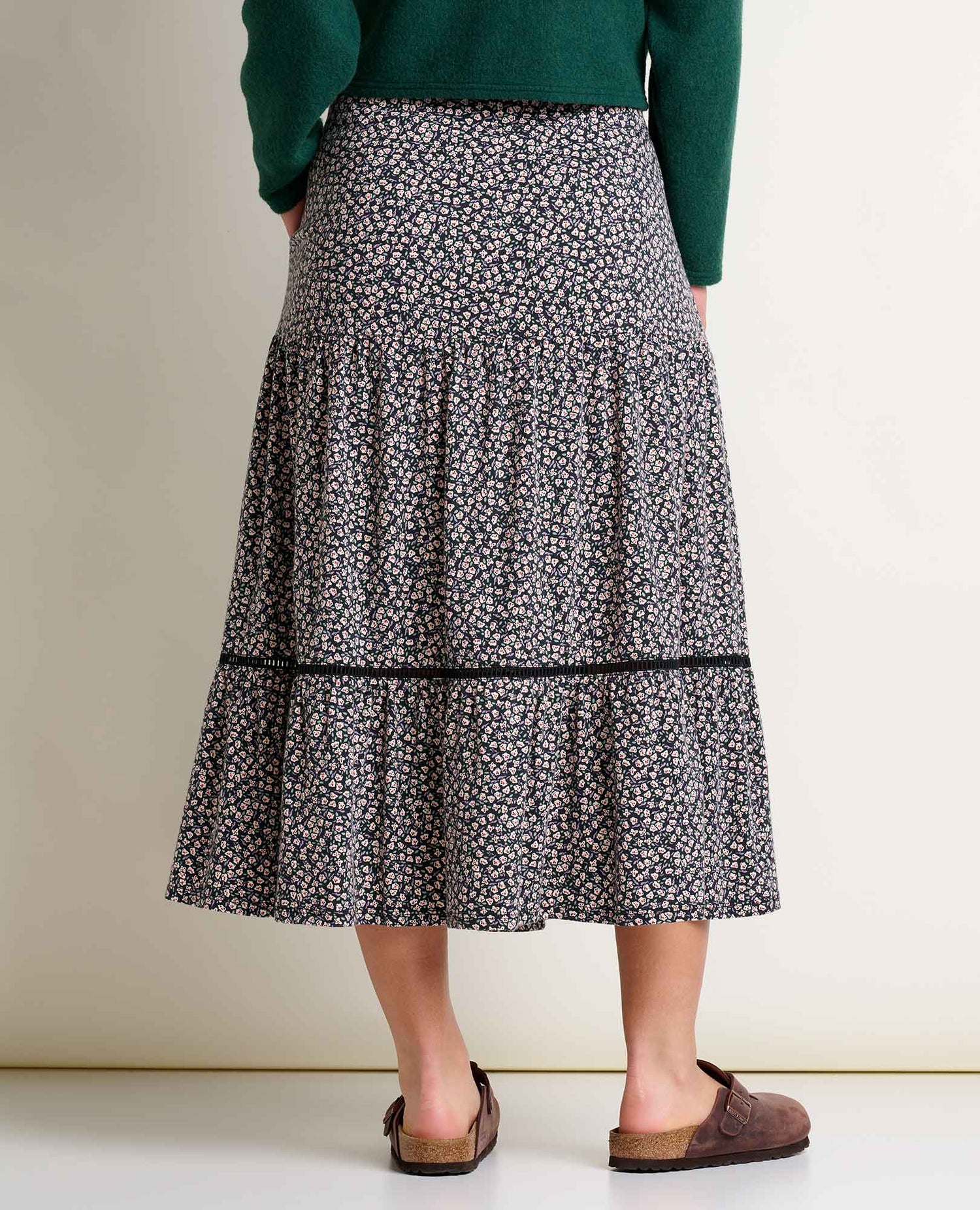 Person wearing a floral skirt with a plain background