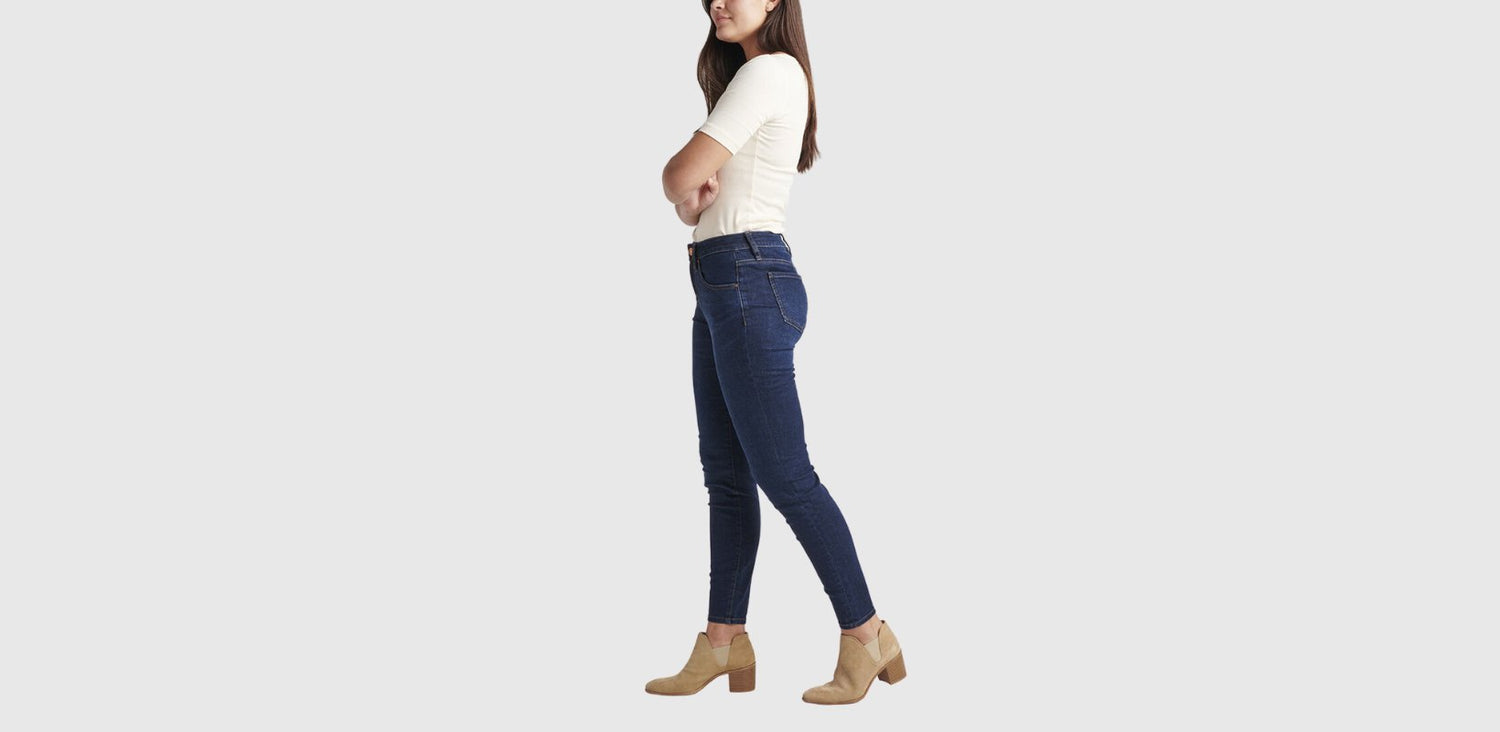 A woman wears a pair of dark skinny jeans and shown from the side.