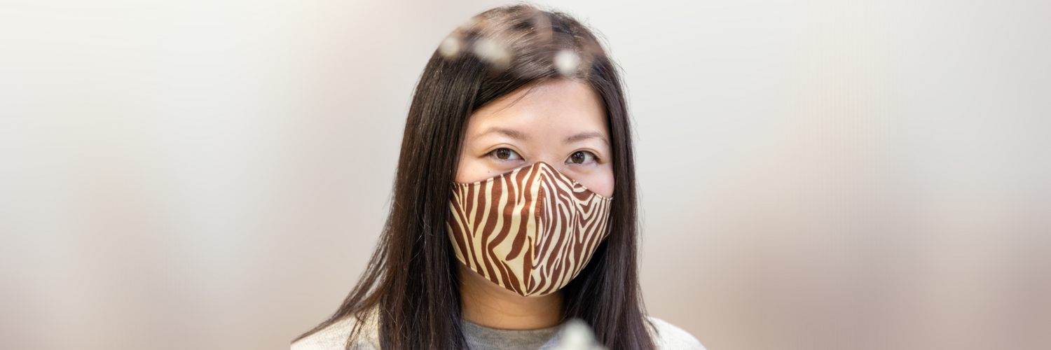 A woman wears a black and white checked face mask.