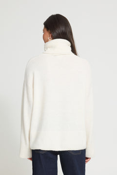 Ichi Kamara Roll Neck Sweater A woman shown from the back wearing a cream-colored, high-neck knit sweater and dark blue jeans against a plain light gray background.