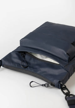 Aunts & Uncles Yura RE Lite Crossbody Bag. A navy blue nylon crossbody bag with an open top zippered pocket, shown on a clean white background.