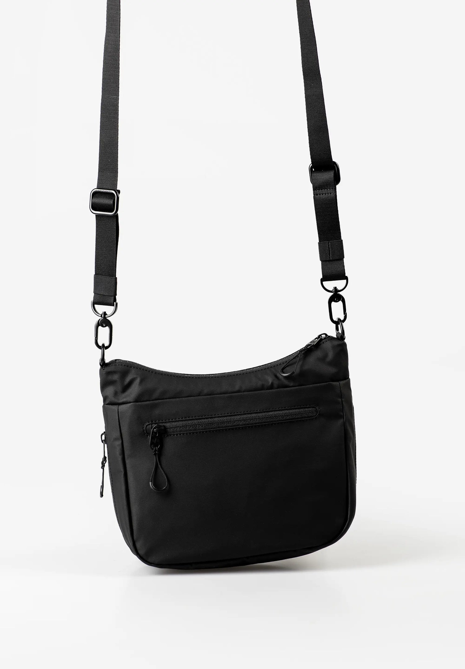 Aunts & Uncles Nanuki RE Lite Crossbody Bag. A black nylon shoulder bag with an adjustable, detachable black strap, featuring a front zippered pocket, photographed against a clean white studio background.