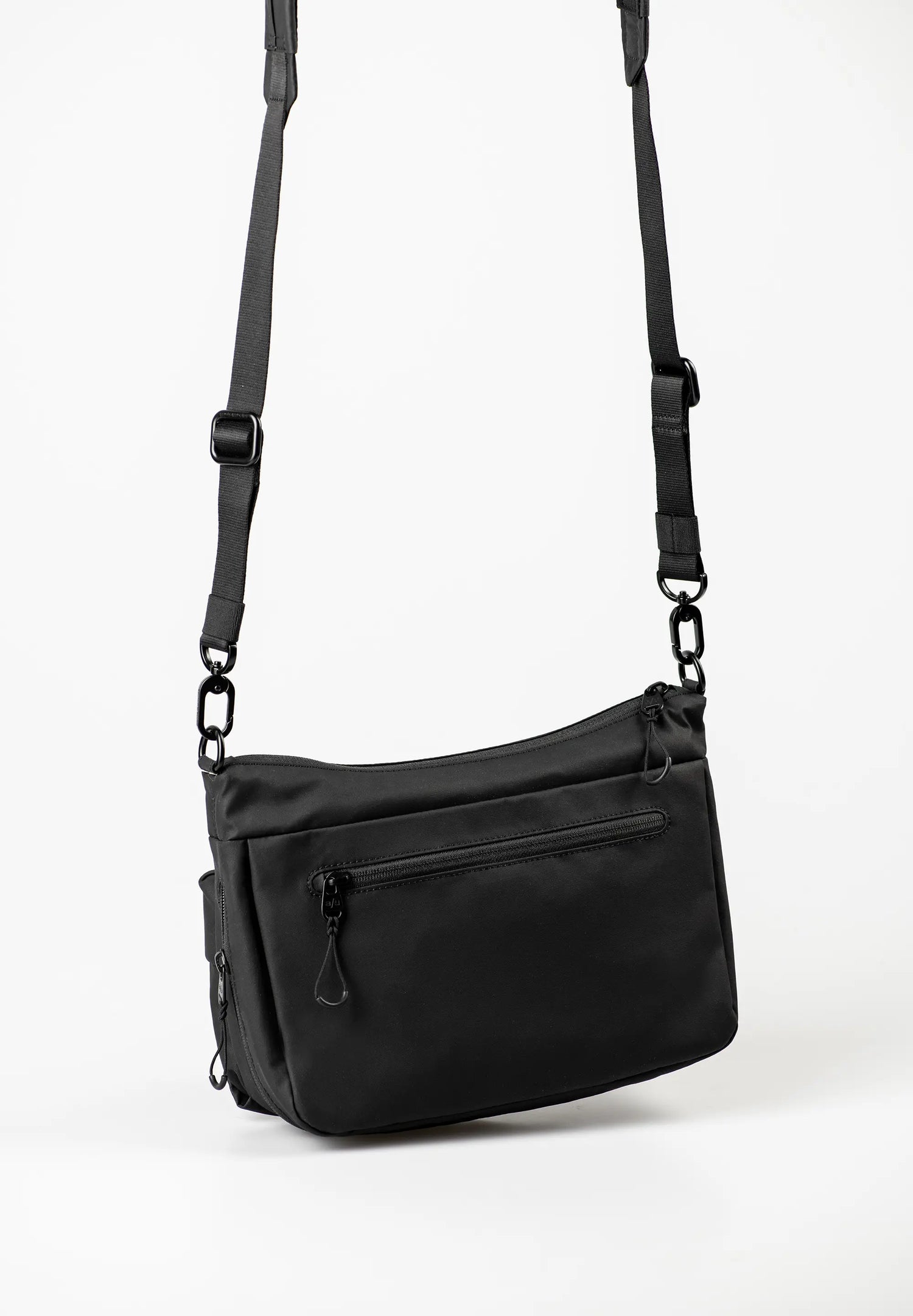 Aunts & Uncles Mogami RE Lite Crossbody Bag. A black nylon crossbody bag with a front zippered pocket and an adjustable shoulder strap, photographed on a clean white studio background.