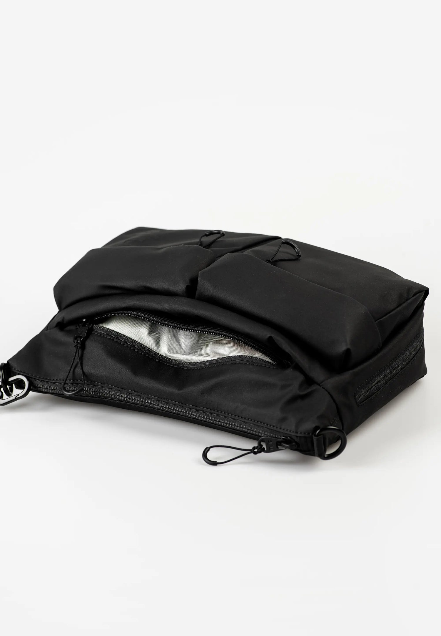 Aunts & Uncles Mogami RE Lite Crossbody Bag. A black nylon utility pouch or small bag with a zippered opening, shown open on a clean white studio background.