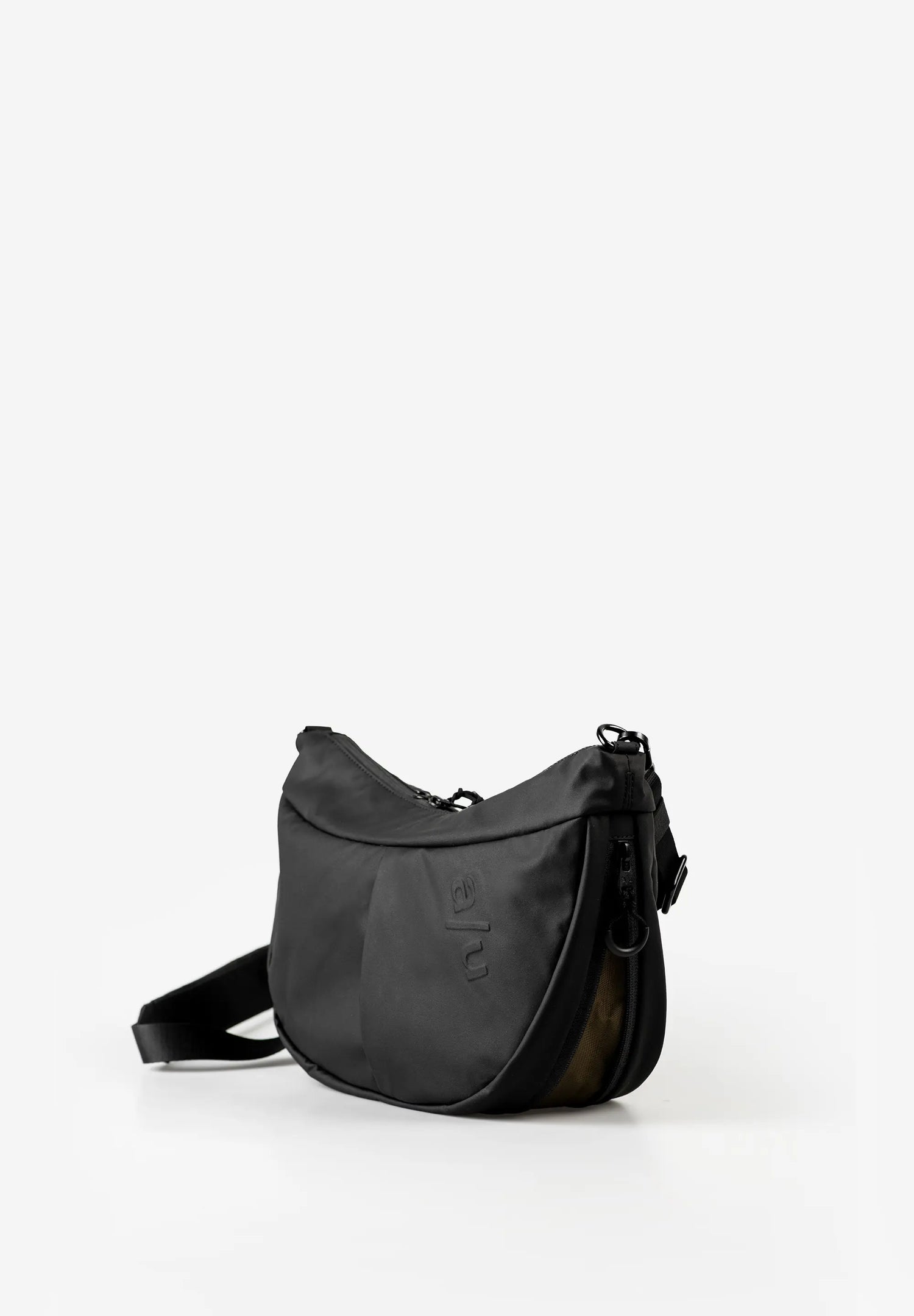 Aunts & Uncles Toyo RE Lite Halfmoon Bag. A black crescent-shaped shoulder bag with a matching black strap, featuring a subtle embossed logo on the front, set against a plain white background.