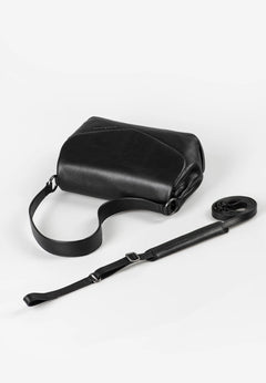 Aunts & Uncles Fern Leather Crossbody Purse. Black leather bag with a strap on a white background
