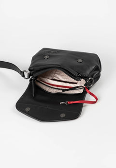 Aunts & Uncles Fern Leather Crossbody Purse. A black leather crossbody bag shown open, revealing a light pink patterned lining, zippered compartments, silver-tone hardware, and a red zipper pull, photographed on a clean white background.