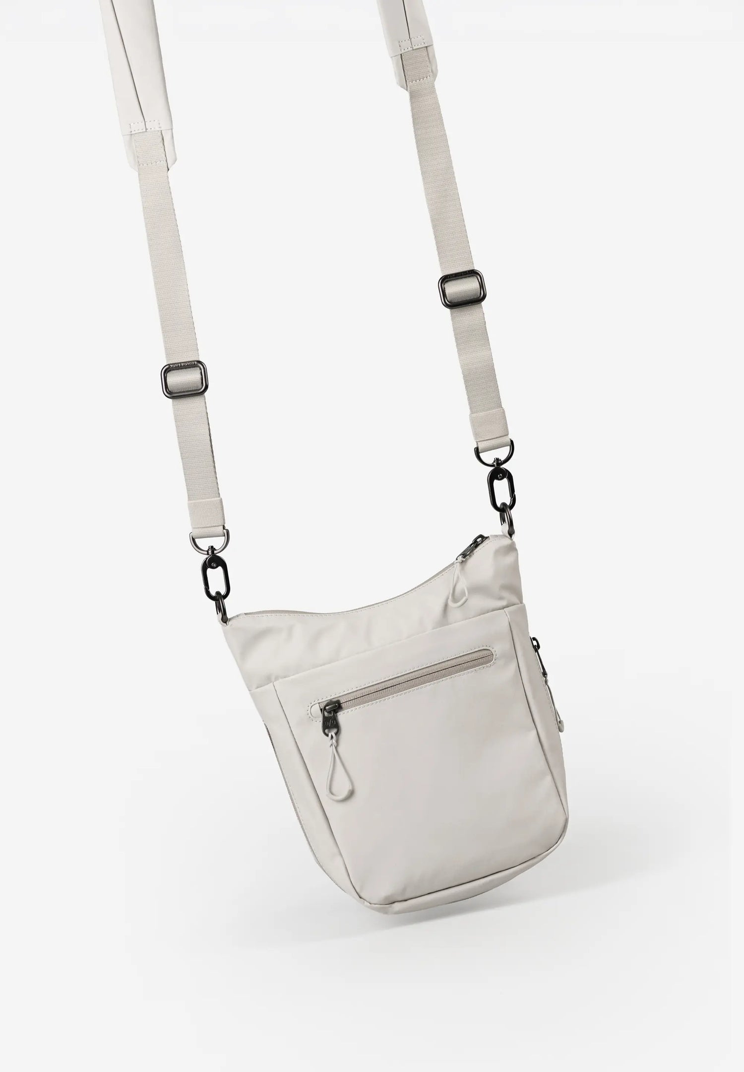 Aunts & Uncles Yura RE Lite Crossbody Bag.A light beige nylon shoulder bag with a matching adjustable shoulder strap and black metal hardware, shown against a plain white background.