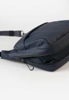 Aunts & Uncles Nanuki RE Lite Crossbody Bag. A dark navy blue nylon crossbody bag with a zippered compartment and adjustable strap, shown on a clean white background.