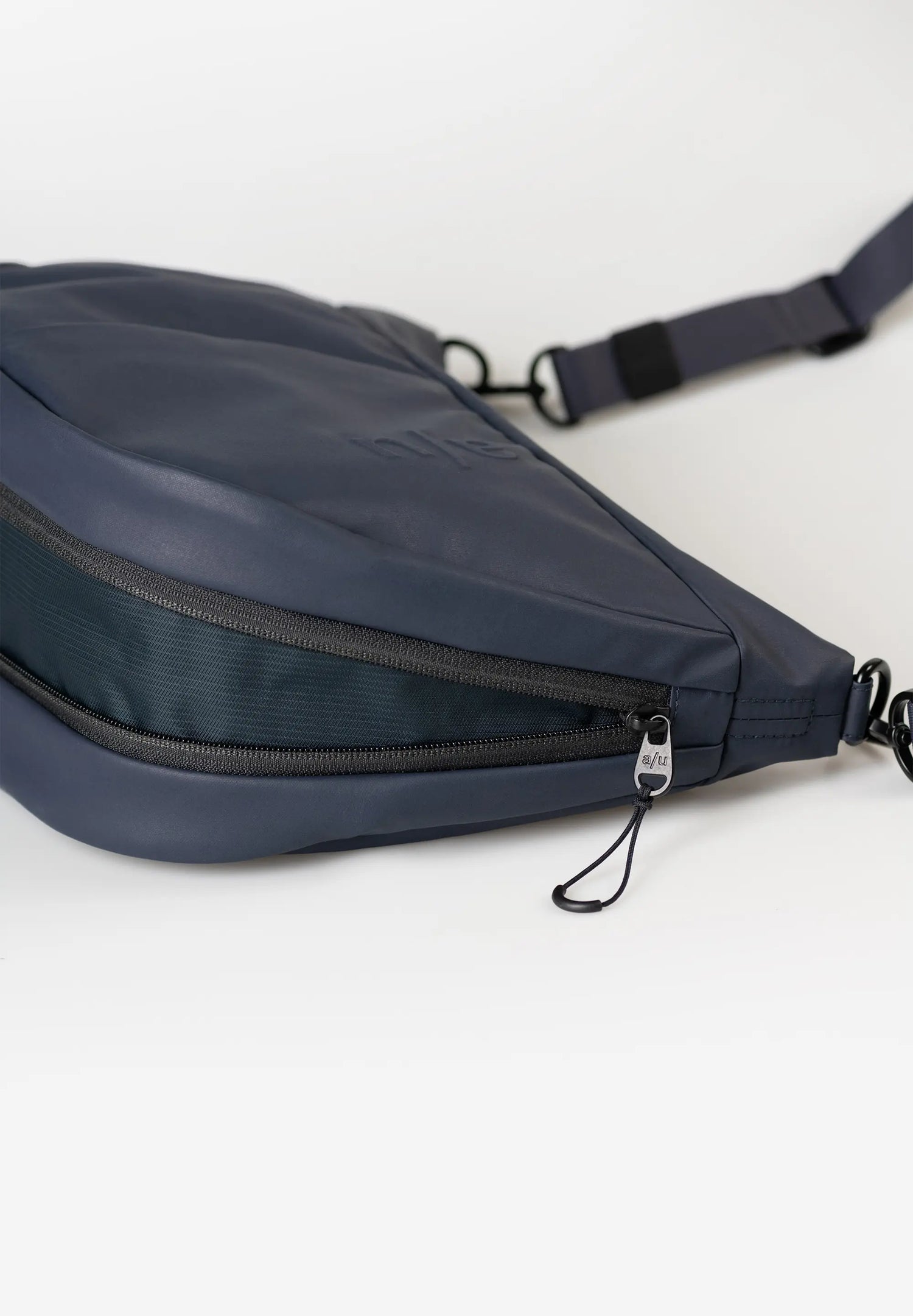 Aunts & Uncles Toyo RE Lite Halfmoon Bag. A navy blue nylon crossbody bag with a zippered compartment and adjustable strap, shown on a clean white background.