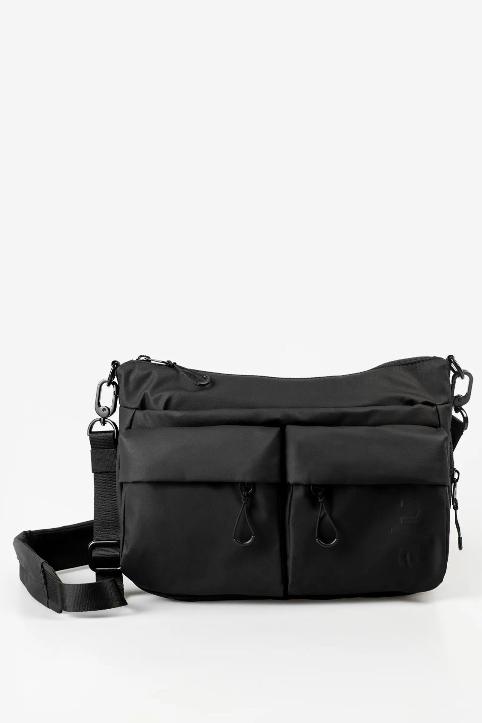 Aunts & Uncles Mogami RE Lite Crossbody Bag. A black nylon messenger bag with multiple front zippered pockets and a detachable shoulder strap, photographed on a clean white studio background.