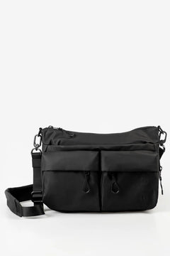 Aunts & Uncles Mogami RE Lite Crossbody Bag. A black nylon messenger bag with multiple front zippered pockets and a detachable shoulder strap, photographed on a clean white studio background.