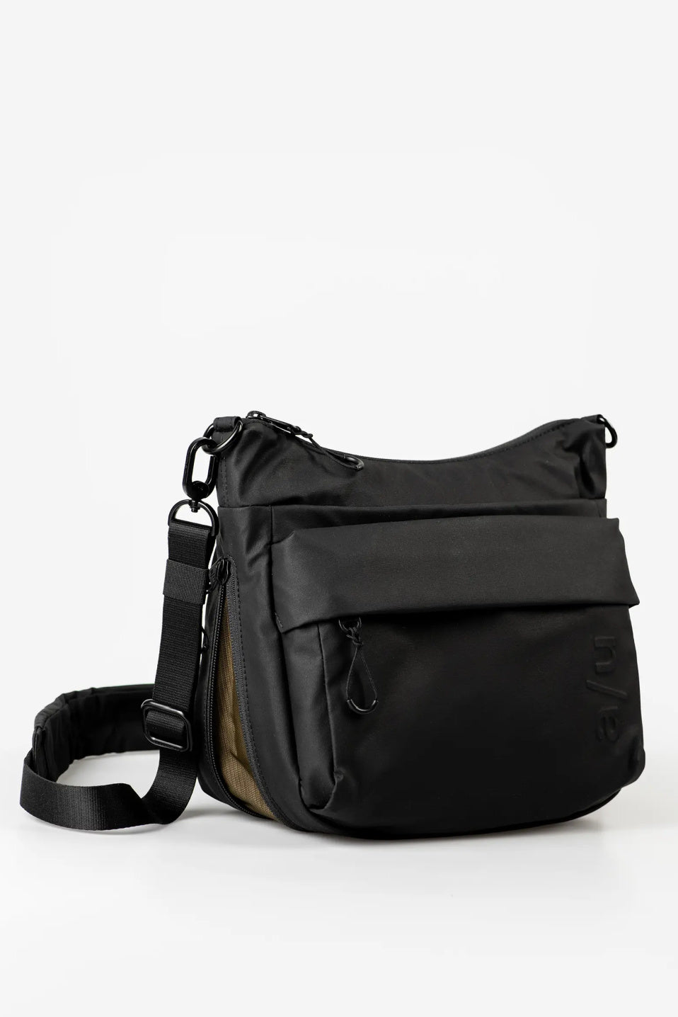 Aunts & Uncles Nanuki RE Lite Crossbody Bag. A black nylon messenger bag with a wide front flap pocket, adjustable shoulder strap, and a brown side panel, photographed on a clean white studio background.