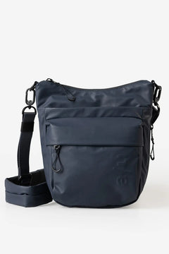 Aunts & Uncles Yura RE Lite Crossbody Bag. A dark navy blue nylon shoulder bag with a front zippered pocket and an adjustable shoulder strap, displayed on a clean white background.