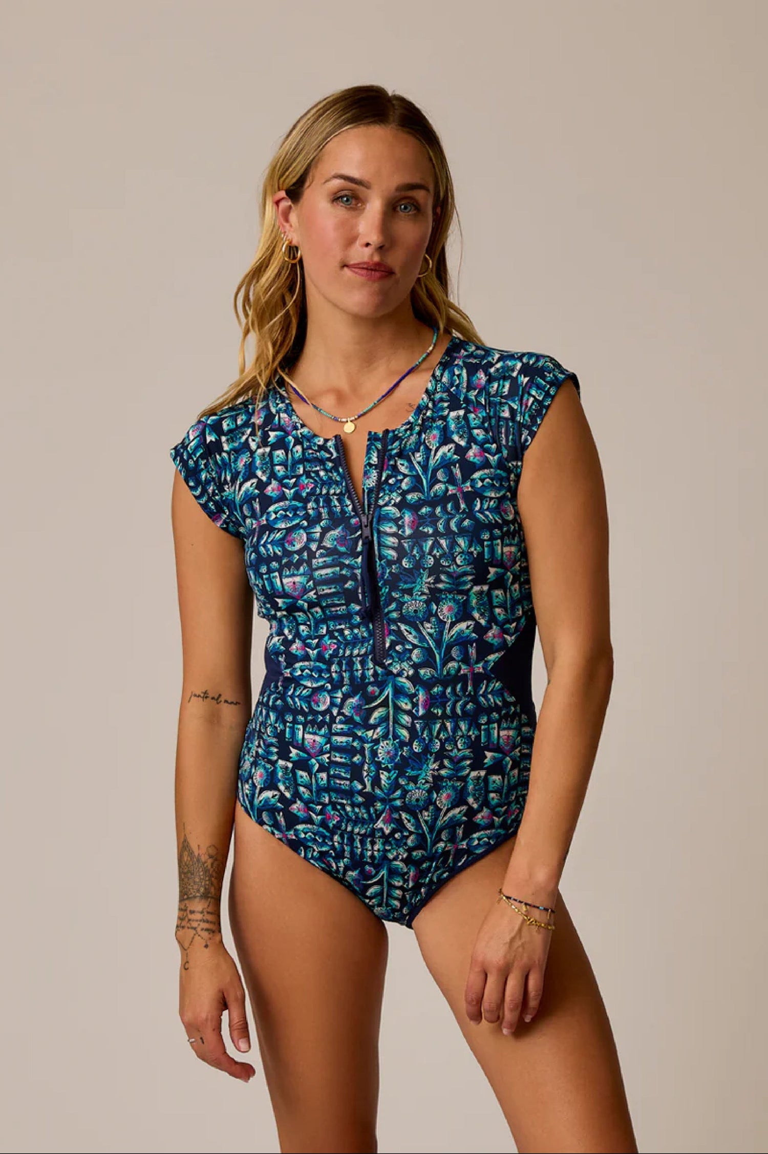 Woman wearing a blue patterned swimsuit against a beige background