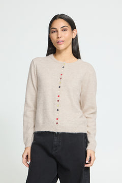 Ichi Fanita Cardigan. A woman modeling a light beige knit sweater with a vertical row of colorful buttons down the front, paired with black pants, against a plain light gray background.